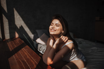 Girl sitting on the bed by the window in the sunlight