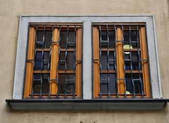 Fototapeta na wymiar Wood Window Pair with Curvy Wrought Iron Bars and Moon Lamp Light in Bratislava Slavakia