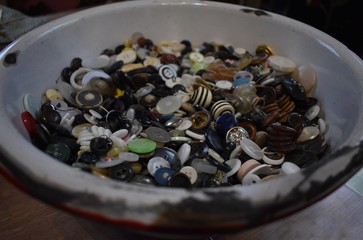 Old metal bowl filled with buttons