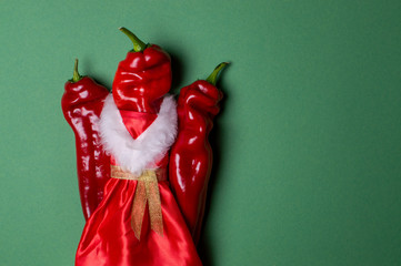New Year pepper on a green background, christmas table products, hot pepper in santa costume