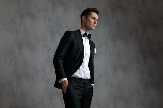 young elegant man wearing tuxedo and holding hands in pockets