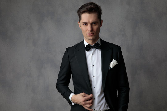 elegant young man wearing tuxedo and holding coat