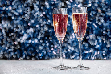 Two beautiful Christmas glasses with splashes and Christmas decorations with bokeh, mysterious new year background.