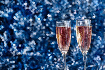 Two beautiful Christmas glasses with splashes and Christmas decorations with bokeh in the foreground, mysterious new year background.