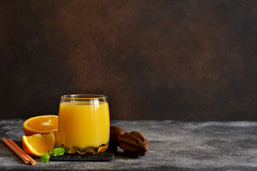 Orange juice, oranges and and juicer on stone background. Horizontal shot.