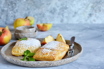 Puffs with apples and cinnamon in a plate on the kitchen table.