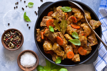 Stew with spices in a pan on a concrete background. View from above.