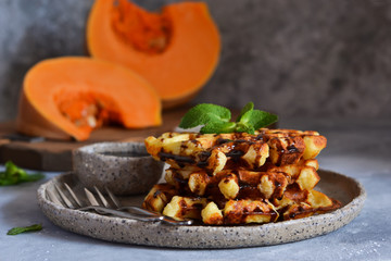 Belgian waffles with pumpkin and chocolate sauce on a concrete background with place for text.