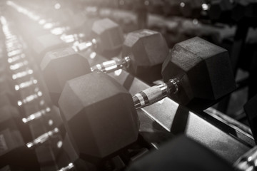 Close up many metal dumbbells on rack in sport fitness center