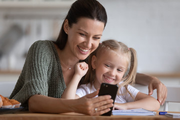 Smiling mother and little daughter taking selfie on phone