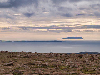 Taken from the rock strewn top of Ronas Hill in Northmavine on Mainland, Shetland, Scotland, UK, the islands of Papa Stour (left) and Foula (right) appear across a calm sea.