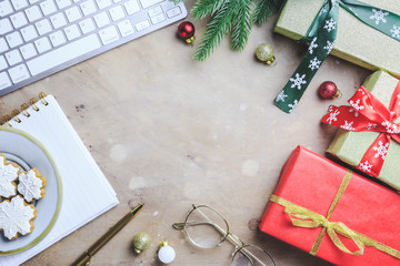 Workspace in Christmas style with keyboard, notebook, glasses, cookies, gift boxes and fir branches on white background. Freelance and work on holidays concept. Top view. Flat lay. Copy Space