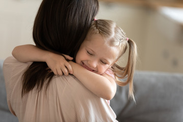 Cute little daughter embracing mother close up, expressing love