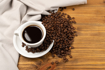 Hot coffee cup and coffee beans on brown background top view