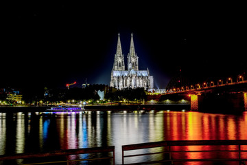 Obraz premium Night View of Cologne Cathedral (Kolner Dom) and Rhine river under the Hohenzollern Bridge, Cologne city skyline at night, North Rhine Westphalia region, Germany.