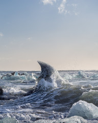 Obraz premium Iceberg shaped like the fin of a large shark gets hit by a wave