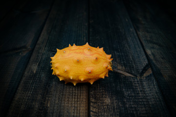 Kiwano on a dark wooden table. The concept of eating fruit, eating meals with vitamins. Taking care...