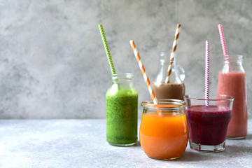 Assortment of colorful smoothies in a bottles with paper straws.