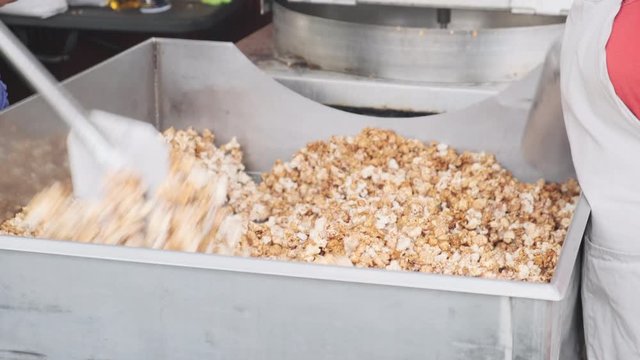Cooks stirring up fresh spiced kettle corn. Handheld. High angle