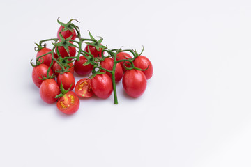 Grape or cherry tomato branch. Pile of red grape tomatoes isolated on white background, soft light, angle view, studio shot.