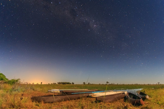 Botswanian local mokoro boats under the starlite sky, on the shore of delta Okavango river, Botswana