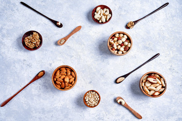 pecans, hazelnuts, almonds, pine nuts, Brazil nut, cashews in wooden bowls on blue background, top...