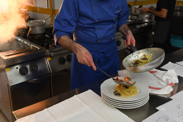 chef in cucina prepara una pentola di spaghetti ai frutti di mare