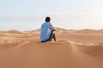 A person sitting in the desert sahara watching the sunrise