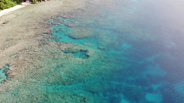 aerial view of untouched pristine coral reefs along a tropical island in the south pacific