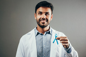 Prostate Cancer Awareness. Doctor man holding light Blue Ribbon for supporting people living and illness. Men Healthcare and World cancer day concept
