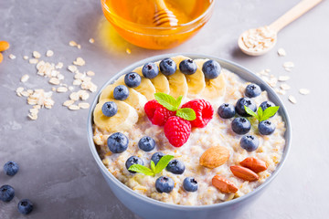 Oatmeal with berries and nuts for breakfast. Oatmeal with fruits, nuts and honey. Oatmeal with blueberries, banana and raspberries. Healthy food
