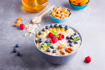 Oatmeal with berries and nuts for breakfast. Oatmeal with fruits, nuts and honey. Oatmeal with blueberries, banana and raspberries. Healthy food
