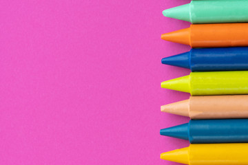 Back to school, minimalism concept. School supplies. Wax crayons on trendy purple color paper background. Copy space, flat lay