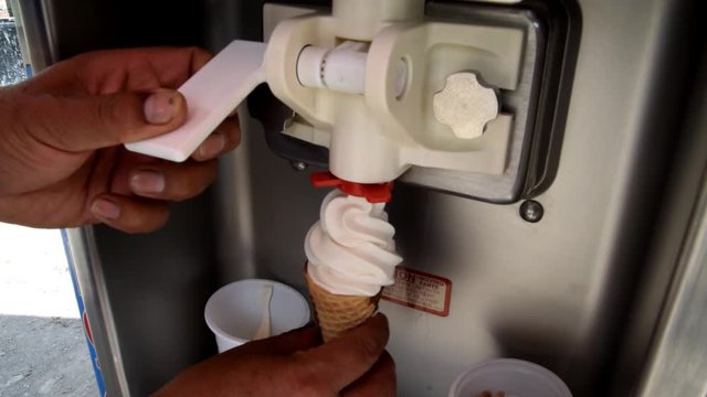 closeup fresh white tasty vanilla ice cream fills slowly little waffle cone by special machine