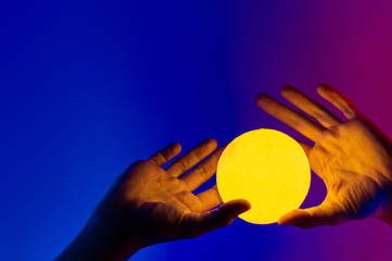Man holding yellow moon shape illuminated sphere