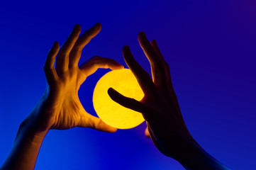 Man holding yellow moon shape illuminated sphere