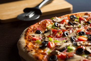 Close-up of fresh homemade Pizza seen from above, on dark wooden table.