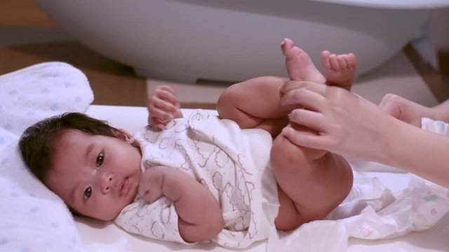 Asian baby infant lying down while her parent changing a diaper, wiping her butt, day light, family activities, warmness, before bath, cleansing, cleanliness, hygiene, 4k