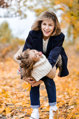 mother and daughter in autumn park have fun