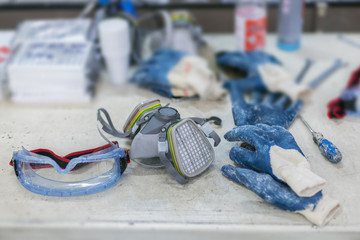 safety goggles, respirator and gloves on factory table - obrazy, fototapety, plakaty