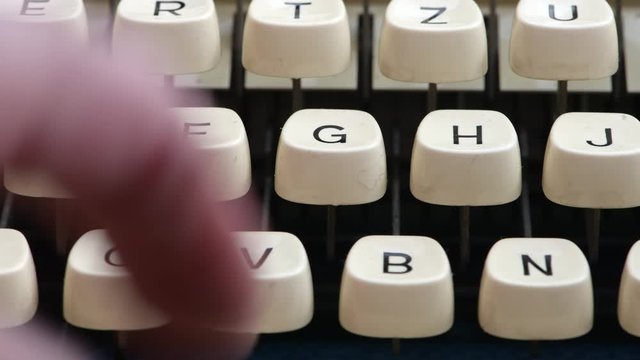 Close up of a 1950's era German typewriter keyboard.  Keys are QWERTZ instead of QWERTY.  Fingers typing.