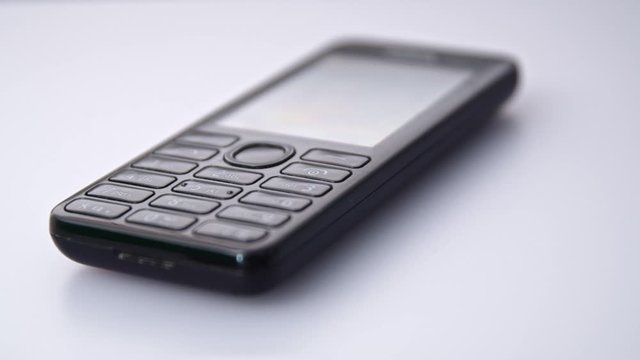 Close Up old Nokia 310 phone on a white table. Tracking left shot