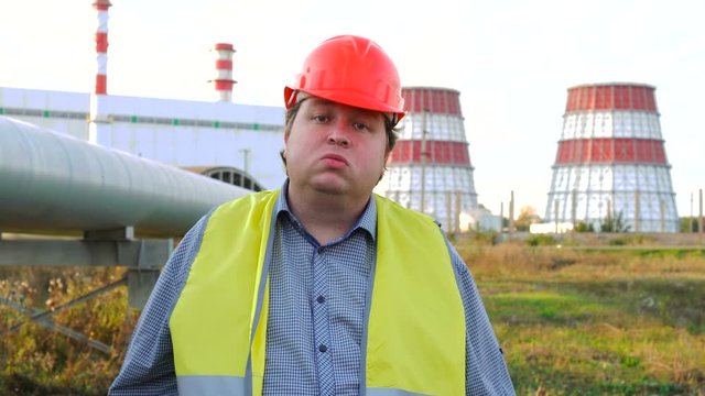 Impudent worker, engineer, or electrician looking directly at the camera and spits in front of a power station