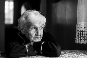 Portrait of a lonely sad old lady. Black and white photo.