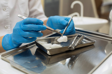 Female dentist hands holding dental tools over medical office background. Medicine, stomatology and healthcare concept.