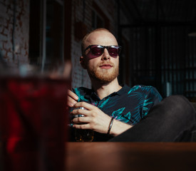 Man in sunglasses drinks lemonade and awaits his lunch
