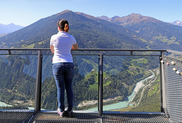 Eine junge Frau steht hoch oben auf einem Aussichtsplatz in den Bergen. Aussichtsplattform der...