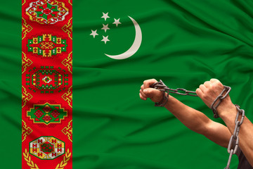 male hands of prisoner in iron chains against background of the national flag of Turkmenistan, concept of political repression, crime, imprisonment, violation of the rights and freedoms of citizens