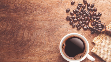 top view coffee bean and wooden scoop and a cup of coffee on wood table