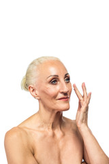 Senior Female Concepts. Portrait Nude of  Senior Caucasian Woman Using Facial Cream. Against White Background.